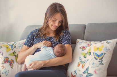 Smiling mother breastfeeding her very young baby on a sofa